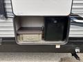 A compartment of a 2021 Jayco Jay Flight showing a small drawer and a black refrigerator visible inside