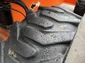 A close-up of a textured tire from a 2012 JLG 660SJ showing water droplets on its surface and a rugged tread pattern designed for traction