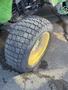 A close-up view of a tire from a 2008 John Deere 3320 300X tractor showing a rugged tread pattern and a yellow rim