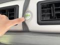 A hand is pointing at a circular air vent control button labeled Valeo on the interior of a 2020 Chevrolet Express van