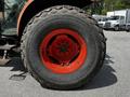 A close-up of a large wheel from a 2011 Kubota M8540D tractor featuring an orange rim and a heavily treaded black tire