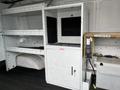 A 2009 Ford Econoline interior featuring built-in shelving and a white cabinet with a glass front