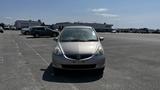 A silver 2006 Honda Fit parked on a paved surface with a clear windshield and a simplistic front design featuring the Honda emblem