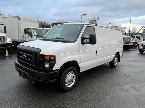 A white 2013 Ford Econoline van with a plain exterior and front grille parked on a roadway