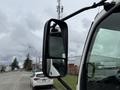 A side mirror of a 2014 Hino 195 truck showing a reflection of the road and surrounding vehicles