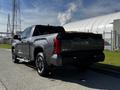 A 2023 Toyota Tundra in grey with a pickup truck design featuring an open bed and a bold tailgate logo