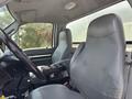 Interior of a 2015 Ford F-750 featuring two gray fabric seats and a black dashboard with control switches and a gear shift