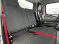 Interior view of a 2021 Mitsubishi FE with two black fabric seats featuring red seat belts and a minimalistic design