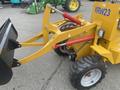 A yellow 2024 AGT KRW 23 Mini loader with a black front bucket and red hydraulic arms runs on rubber tires with steel rims