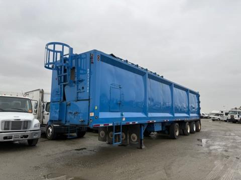 A blue 2011 Freightliner Cascadia Nordic truck with a large enclosed cargo area and multiple wheels positioned in a parking area