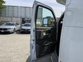 A 2020 Chevrolet Express van with the driver's side door open displaying the interior door panel and cup holders