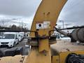 A yellow 2015 Vermeer Corporation BC1200XL wood chipper showing the top of the chute with a warning label and metal components in the foreground