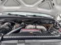 The engine compartment of a 2003 Ford F-450 SD featuring a Power Stroke V8 turbo diesel engine with various mechanical components and pipes visible
