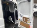 A 2017 Ford Transit Connect with its rear doors open revealing the cargo area featuring a flat floor and minimal storage equipment