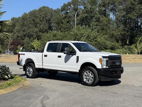 A 2017 Ford F-350 SD in white with a black bed and chrome accents parked with its doors open and a four-wheel drive badge visible