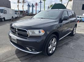 A 2015 Dodge Durango in gray with chrome accents parked with a detailed view of its front headlights and grille