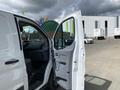 A white 2019 Ford Transit van with its front doors open showcasing the driver's seat and dashboard inside