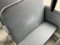 A close-up view of a gray vinyl bus seat with a slightly worn spot on the backrest and no visible seatbelt