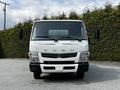 A 2015 Mitsubishi Fuso FE truck facing forward with a white body and orange clearance lights on the roof