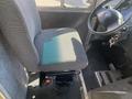 A driver's seat in a 2012 Ford Econoline with a cloth cover and visible seat controls along with a steering wheel and key ignition