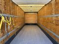 A 2015 Freightliner M2 106 interior with wooden walls and a flat floor featuring metal tracks and yellow tie-down straps along the sides