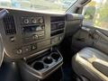 Interior of a 2021 Chevrolet Express showing the dashboard with audio controls and air vents alongside a driver seat and cup holder space