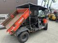 A 2011 Kubota RTV 1140 CPX utility vehicle with a cargo bed tilted upwards revealing its contents and a cab with a protective canopy