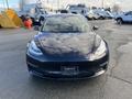 A 2019 Tesla Model 3 facing the camera with a sleek, modern design and distinctive headlights