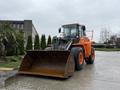 A 2018 Doosan DL300-5 wheel loader with an orange and black color scheme features a large front bucket and is equipped for heavy lifting and moving tasks
