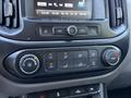 The interior dashboard of a 2018 GMC Canyon featuring climate control buttons and a display screen with radio stations and settings
