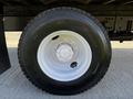 A close-up view of a wheel and tire on a 2016 Freightliner M2 106 featuring a silver rim and a black tire with a tread pattern
