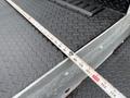 A close-up of a measuring tape placed on the textured surface of a 2015 Ford F-350 SD truck's bed