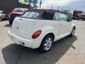 A white 2005 Chrysler PT Cruiser convertible parked with a black soft top and silver alloy wheels