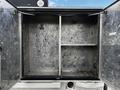 An open storage compartment of a 2007 Ford F-550 with metal walls and empty shelves