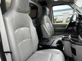 Interior of a 2011 Ford Econoline showing two grey vinyl front seats and a console between them