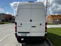 A white 2012 Mercedes-Benz Sprinter van viewed from the rear with a logo on the back and sliding doors