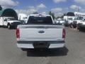 A 2022 Ford F-150 seen from the rear with a white exterior and a visible tailgate featuring the Ford logo and model name