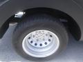 A close-up view of a silver wheel with multiple circular holes mounted on a black tire belonging to a 2016 Ford Transit