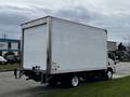 A white 2018 Isuzu NRR box truck parked with a blank rear cargo area and a low profile design featuring dual rear wheels and sideview mirrors
