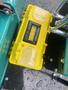 A yellow toolbox labeled Tools Box on a mini excavator, with water droplets on its surface and visible compartments for tool storage