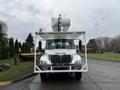 A white 2007 International 4200 truck with an elevated aerial work platform mounted on the back facing forward