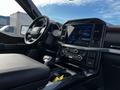 Interior view of a 2021 Ford F-150 showing the steering wheel and center console with a large touch screen display and various controls