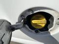 Close-up of the fuel cap for a 2012 GMC Savana showing a yellow gas cap with instructions to tighten until one click