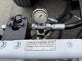 A hydraulic pressure filter with a gauge and attached hoses on a 2016 Peterbilt 348 truck