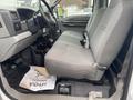 Interior of a 2003 Ford F-450 SD with gray fabric seating and a black floor mat featuring a piece of paper on the floor