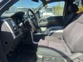 Interior of a 2014 Ford F-150 showing the driver's seat dashboard and center console with controls and armrest
