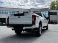 A white 2020 Ford F-350 Super Duty truck is parked with a view of its rear and the tailgate displaying the Super Duty logo