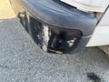 A black plastic rear bumper of a 2014 Chevrolet Express with noticeable scratches and scuff marks on the surface
