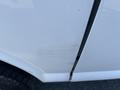 A white 2013 Chevrolet Express showing a long scratch on the side door with a visible indentation on the surface