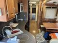 A 2008 Newmar Canyon Star 36 Foot Class A Motorhome featuring a kitchen area with wooden cabinets a sink and a dining table with seating visible in the foreground